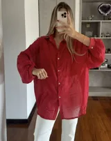 Camisa roja traslúcida con pequeños lunares brillantes, cuello clásico, corte holgado y mangas largas con puños abotonados.