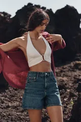 Shorts de denim blanco, tiro alto, estilo mom fit, con cinco bolsillos y cierre frontal con cremallera y botón.