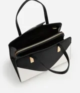 Bolso satchel mediano bicolor, negro en la parte superior y blanco en la inferior, con detalles metálicos dorados en las asas. Incluye correa larga desmontable y cierre de cremallera.