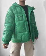 Campera acolchada color verde con capucha y detalle de elástico ajustable en la parte baja.
