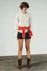 Top de encaje color blanco, con cuello redondo, mangas largas acampanadas y detalle de tachas metálicas en cuello y hombros. Cierre en la espalda con abertura y botón.
