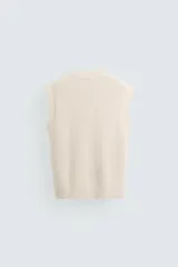 Chaleco de punto color crema con cuello en V y sisas.