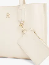 Cartera tote color crema con doble asa de mano y correa larga de tela ajustable y removible. Tiene un monedero extraíble con cierre y logo en relieve, cierre magnético y el monograma TH en la parte delantera.