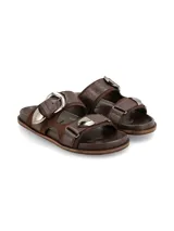 Sandalias marrones con doble tira de cuero y hebillas metálicas plateadas.