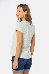 Remera color crema con estampado de hojas azules, de manga corta y cuello redondo.