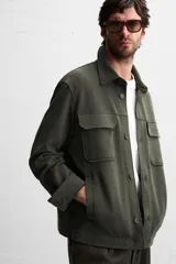 Sobrecamisa color beige de corte relaxed fit, con cuello solapa, manga larga con puños abotonados, bolsillos de plastrón con solapa en el pecho y bolsillos de vivo en la cadera. Cierre frontal con botones.