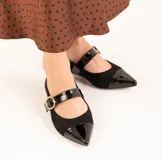 Zapato guillermina de gamuza negra con puntera de charol brillante y tira sobre el empeine con hebilla dorada. Tacón bajo y cuadrado.