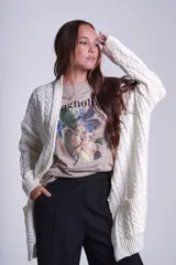 Saco tejido color crema con diseño de ochos y bolsillos frontales.