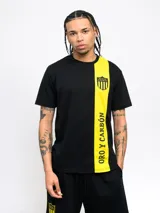 Remera de poliéster y algodón con diseño de dos mitades, una negra y otra amarilla, con escudo del Club Atlético Peñarol y la leyenda "Oro y Carbón".