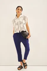 Pantalón babucha azul con elástico en la cintura y cordón de ajuste con terminaciones metálicas. Tiene bolsillos diagonales en el frente y falsos bolsillos ojal en la espalda.