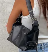 Cartera tipo baguette de cuero sintético color borgoña, con doble cierre superior y correa corta de hombro con hebillas metálicas.