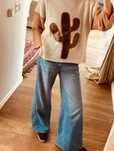 Sweater de punto color crema con mangas color camel y aplique de cuero marrón en forma de cactus en el frente.