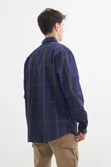 Camisa azul a cuadros grises de manga larga con cuello abotonado y bolsillo en el pecho.