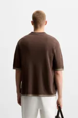 Camisa marrón de punto con viscosa, corte relaxed fit, cuello solapa, manga corta y cierre frontal con botones.