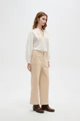 Pantalón de algodón color beige, de tiro alto, corte ancho y largo, con bolsillos frontales tipo parche.