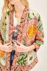 Saco corto estilo kimono con bordado gudri y estampado floral en tonos naranja, verde y gris.