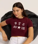 Remera corta color bordó de algodón con elastano, cuello redondo y mangas cortas. Estampa frontal con letras "NYC" y el número "2002" con una estrella en el medio.