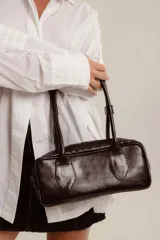 Cartera tipo baguette de cuero color amarillo pálido, con asas cortas y estructura rectangular.