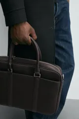 Maletín marrón con textura grabada, cierre de cremallera, bolsillo interno para dispositivos electrónicos de hasta 13 pulgadas, bolsillo frontal con cremallera, doble asa de mano y asa de hombro ajustable y extraíble.