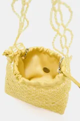 Bolso mini tipo saca color amarillo, con cuerpo de abalorios, asa de hombro y asa bandolera de cadena. Bolsita interior con cierre fruncido.