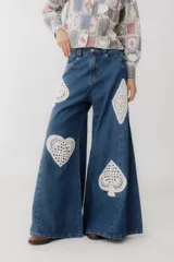 Pantalón de jean azul de corte wide leg con aplicaciones de crochet en forma de corazón, trébol, diamante y pica.