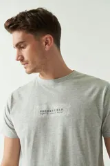 Remera gris de manga corta con cuello redondo y estampado con el logo de la marca y diseño de hojas.