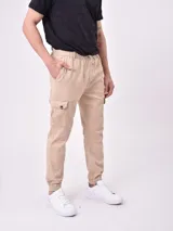 Pantalón jogger color beige con cintura elástica ajustable con cordón, bolsillos laterales y bolsillo cargo con solapa en la pierna.