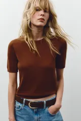 Jersey de punto negro, cuello redondo y manga corta, con acabados en rib en cuello, puños y ruedo.