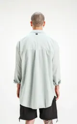 Camisa manga larga verde agua, de calce oversize con bolsillo ojal en delantero y cartera escondida.
