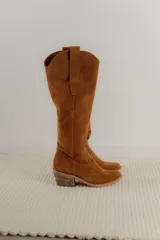 Bota alta de cuero color beige, estilo texana, con caña alta y taco bajo.