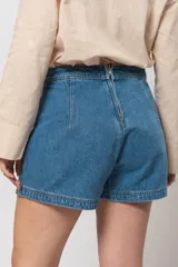 Short pollera de jean de tiro alto, color celeste, con cierre trasero invisible y detalle de bolsillos delanteros.