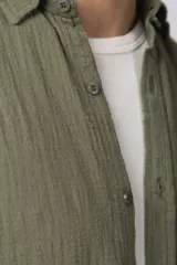 Camisa de lino blanca de manga larga, con cuello clásico y cierre frontal con botones. Corte recto y holgado.