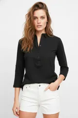 Remera azul marino de manga 3/4, con cuello camisero y cierre frontal parcial con botones. Diseño holgado con bolsillos frontales.