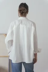 Camisa blanca de manga larga con cuello clásico y cierre frontal con botones.