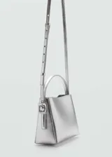Bolso mini tipo bucket plateado, con asa de mano rígida y correa bandolera fina ajustable.