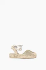 Alpargata dorada con suela de yute y tiras para atar al tobillo.