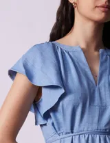 Vestido midi celeste de tencel con cuello a la base y escote en V. Cintura con frunces y lazo de ajuste. Terminación de ruedo con volado.