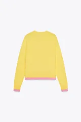 Chaqueta de punto amarilla con cuello redondo, manga larga y cierre frontal con botones negros. Presenta ribetes rosas en cuello, puños y bajo.