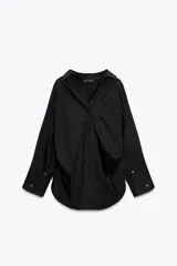 Camisa negra de cuello solapa y manga larga amplia. Tiene un bolsillo de parche en el delantero, detalle de pliegues y cierre frontal con botones.