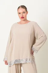 Blusa color beige con cuello redondo y mangas largas, con detalle de lentejuelas plateadas en el ruedo y los puños.