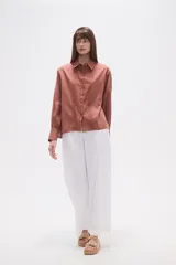 Camisa blanca de broderie con cuello camisero, cierre frontal de botones, mangas largas y corte holgado.