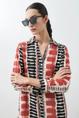 Vestido camisero midi con estampado abstracto en tonos beige, rojo y negro.