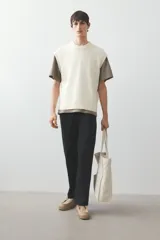 Chaleco de punto color crema con cuello redondo y ribete acanalado en cuello, sisas y bajo.