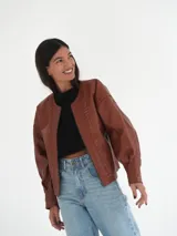 Campera oversize de cuero color marrón con cierre frontal y detalles de costuras en los bordes.