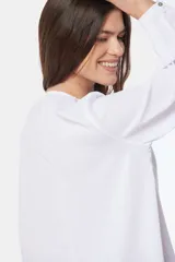 Blusa de manga larga blanca con botones forrados en el pecho y doble capa en el frente.