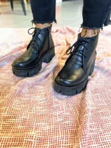 Botas acordonadas color beige con plataforma track color negro y cierre lateral.