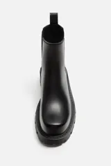 Bota Chelsea negra de cuero sintético, con elásticos laterales, tirador trasero y suela track.