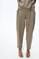 Pantalón color arena de tiro medio con cintura elástica, bolsillos laterales ocultos y pinzas en el delantero.