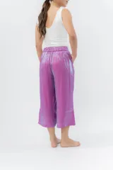 Pantalón de lino con acabado metalizado tornasolado, que refleja tonos entre rosa y lila según la luz. De corte recto y largo ¾, tiene cintura con elástico en la espalda que aporta comodidad y un calce relajado.