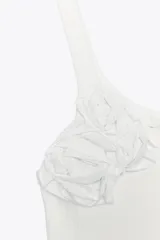 Top blanco de morley con escote redondo y tirantes. Detalle de flor en relieve combinada al tono.